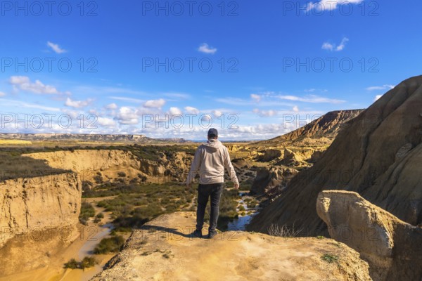 Tourist standing on cliff edge admiring the stunning landscape of bardenas reales desert in