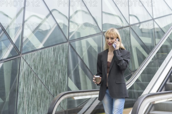 Entrepreneurial girl in business park in a modern building with escalator, young blonde in a suit