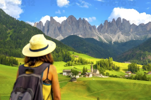 Woman with a backpack enjoying the serene summer landscape of santa maddalena village in val di