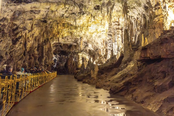 Tourists visiting the magnificent postojna cave in slovenia, riding an electric train through