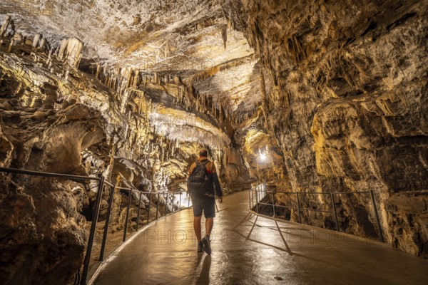 Tourist exploring postojna cave, a renowned natural wonder in slovenia, marveling at the stunning