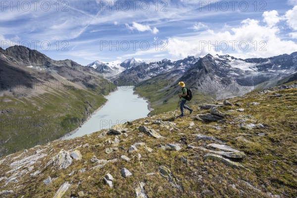 Mountaineer on the summit of Mont de la Blana, view of a blue mountain lake, Lac des Dix reservoir,