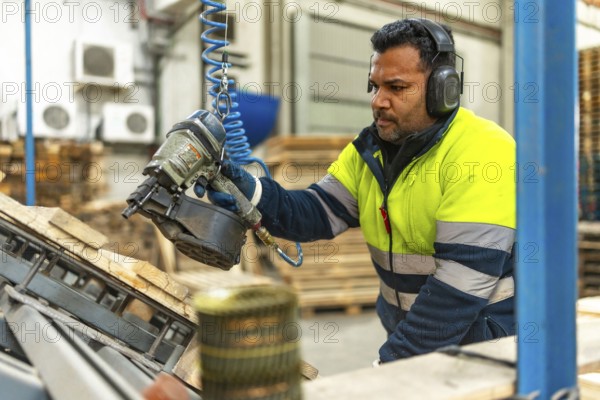 Man caucasian adult, worker in protective work gear recycling pallets in a factory of a recycling