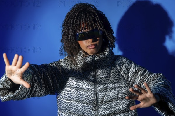 Fashionable woman with curly hair wearing futuristic sunglasses and animal print jacket making stop