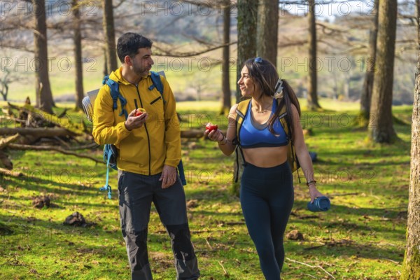 Hikers enjoying a healthy snack of apples while walking through a sunny forest during their outdoor