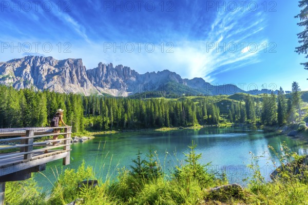 Female tourist admiring the stunning turquoise waters of lake carezza with the latemar mountain