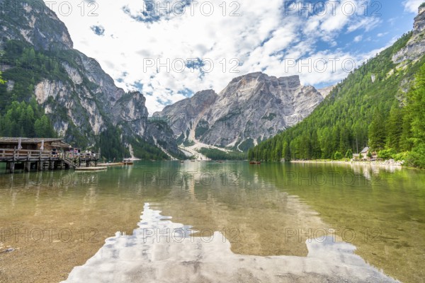 Crystal clear waters reflecting majestic peaks and lush forests create a breathtaking panorama at