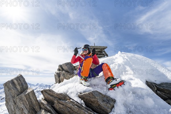 Happy mountaineer with ice axes and crampons on the summit of Piz Grialetsch in winter, Graubünden