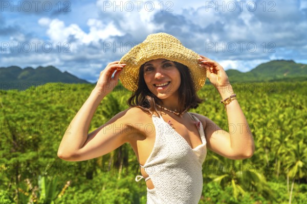 Young woman enjoying a sunny day in a coconut plantation in siargao island, philippines, holding