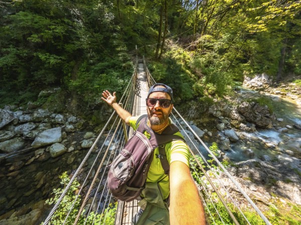 Hiker taking selfie while crossing hanging bridge over tolmin gorge in triglav national park,