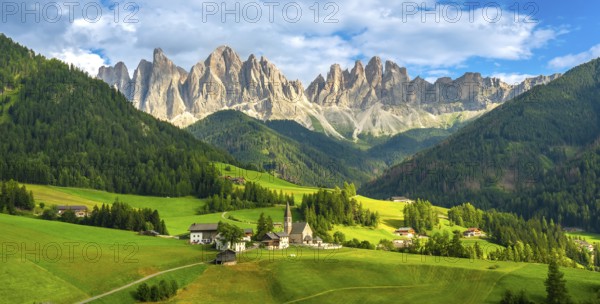 Green meadows, traditional houses, and the iconic santa maddalena church create a picturesque scene