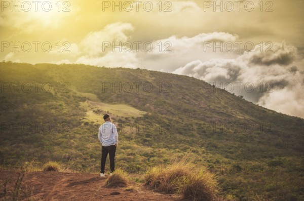 Rear view of a lonely man on top of a hill looking at the horizon. Back view of lonely man on a