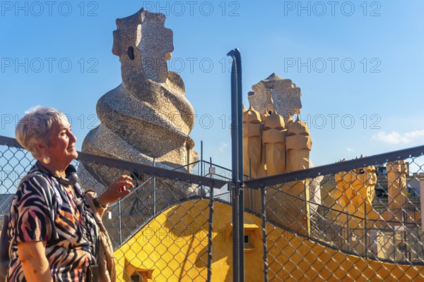 Senior tourist admiring the whimsical chimneys and vibrant architecture of casa mila, a unesco