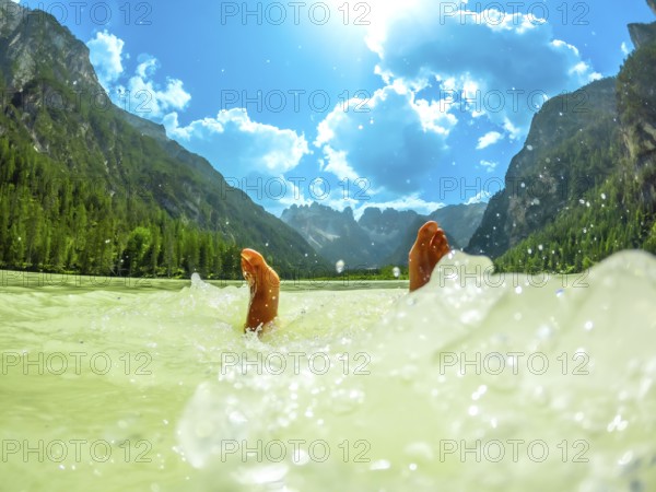 Feet of a tourist splashing in the turquoise water of lago di landro or durrensee lake, with the