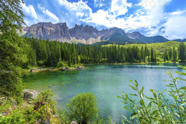 Emerald waters of lake carezza reflecting latemar mountain range in the dolomites, italy, on a