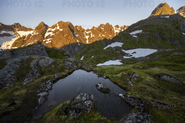 Rocky mountain peaks with reflection, small pond in moor landscape at Trollfjord Hytta, mountain