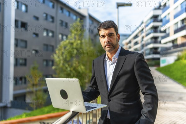 Portrait of a mature adult caucasian elegant and confident businessman using laptop standing in the