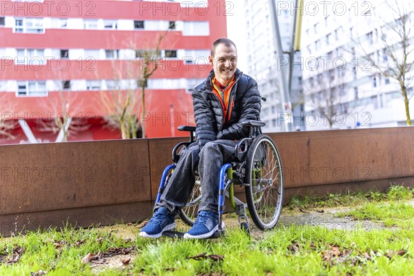 Young man with disability smiling in his wheelchair enjoying a day out in an urban park, promoting