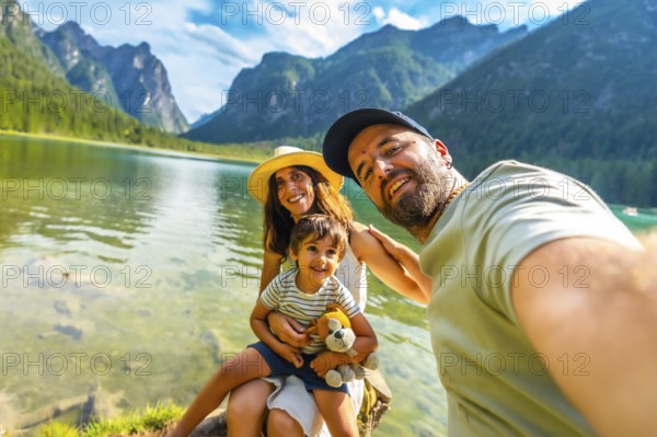 Tourists enjoying summer holidays by a picturesque alpine lake, capturing joyful moments with their