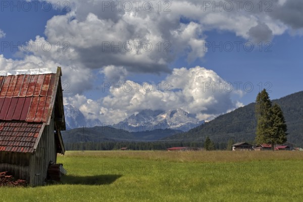 A peaceful alpine landscape with meadows, an old barn and mountains in the background, Wallgau,