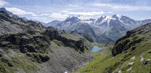 Mountain stream and mountain lake Lac de Louvie with glaciated summit of the Grand Combin, Val de