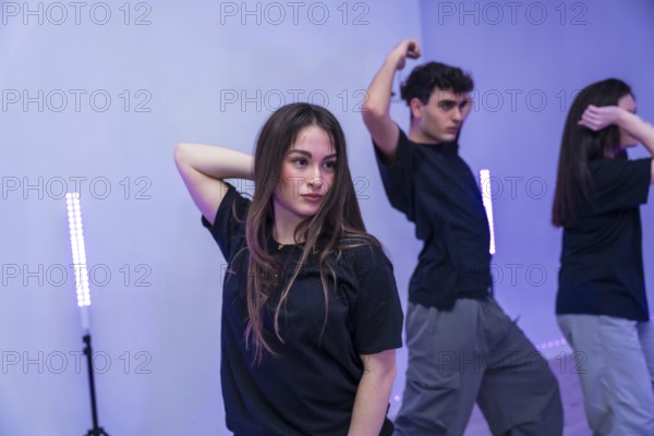 Group of young dancers practicing a modern choreography in a dance studio illuminated by purple