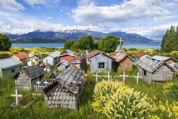 Colourful plastic flowers and graves with miniature houses made of corrugated iron and wooden