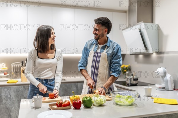 Young smiling couple preparing a healthy salad together in their modern kitchen, enjoying their