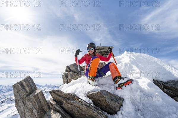 Happy mountaineer with ice axes and crampons on the summit of Piz Grialetsch in winter, Graubünden