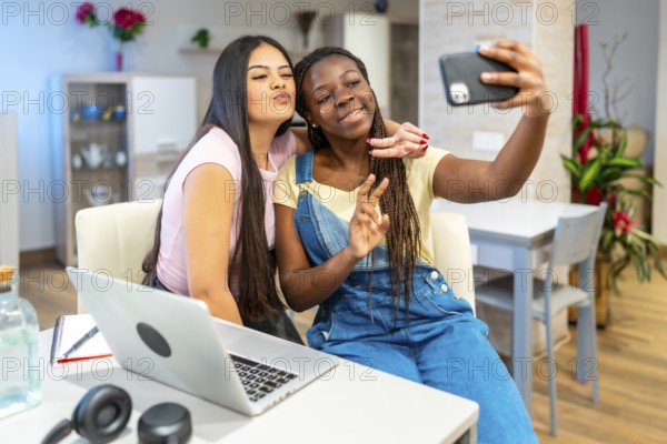 Two friends enjoying a cheerful moment, taking a selfie with a smartphone while studying together