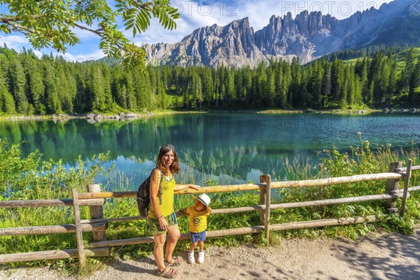 Mother and child enjoying summer holidays at the magnificent lake carezza with the latemar massif
