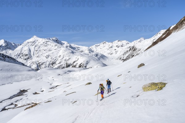 Two ski tourers in a mountain landscape with snow, behind Piz Müsella, ascent to Grialetsch