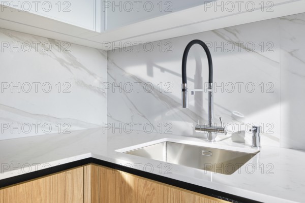 A contemporary kitchen showcases a stylish sink integrated into smooth marble countertop. The