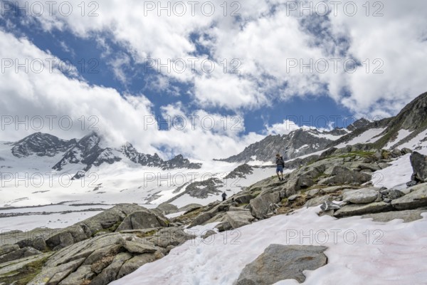 Mountaineer on a hiking trail between snow, descent from the summit of Schönbichler Horn, view of