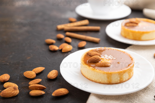 Sweet tartlets with almonds and caramel cream with cup of coffee on a black concrete background and