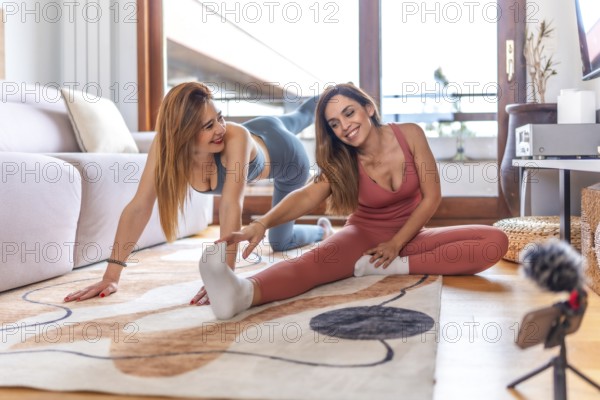 Two friends engaged in an online yoga class, practicing stretching and meditation in a cozy living