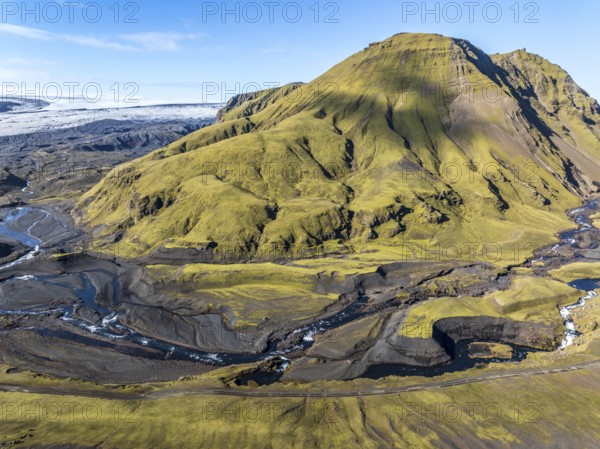 River along road F232 Öldufellsleid, slopes of Mt. Öldufell, moss-covered hill in black lava sand,