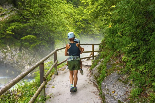 Mother carrying her child while hiking on a misty summer day in vintgar gorge near bled, slovenia,