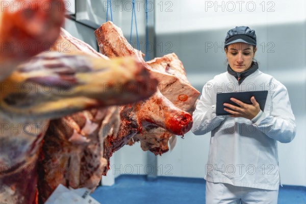 Woman using tablet doing quality control tasks in a meat processing factory