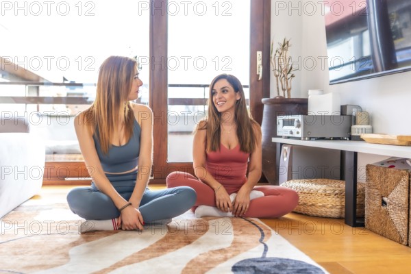 Two friends engaging in an online yoga class, meditating in a cozy living room. They enjoy a