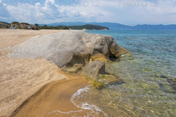 Rocky beach with clear sea water and gentle waves, surrounded by nature, beach, rocks in the shape
