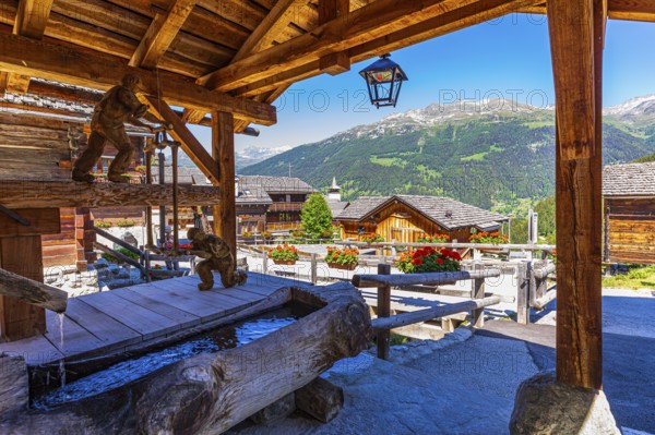 Wooden sculptures with sawmill motifs on the village square, historic village centre, Grimentz, Val