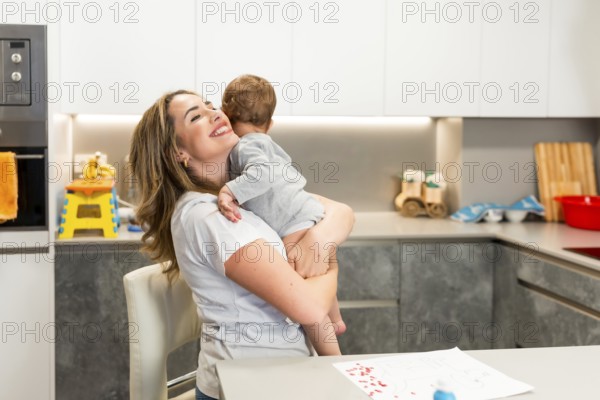 Mom lovingly embraces her baby in a modern kitchen, creating a heartwarming moment of family