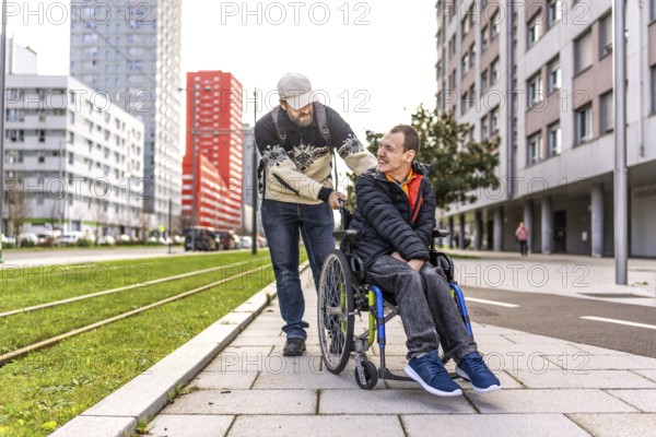 Caregiver assisting a young man with disability, strolling through a city environment, promoting