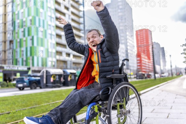 Young man in a wheelchair, raising his arms in celebration, embracing freedom and joy in a vibrant