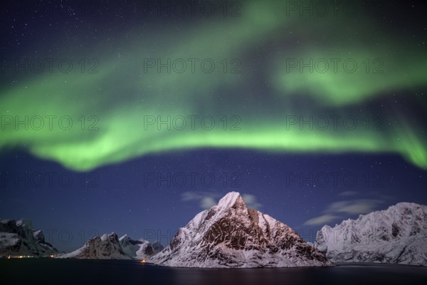 Green northern lights reflected in fjord, steep mountains, aurora borealis, winter, Reine,