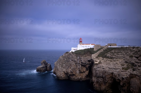 Sailing boat in front of the lighthouse Farol do Cabo de São Vicente, Cape St. Vincent, Sagres,