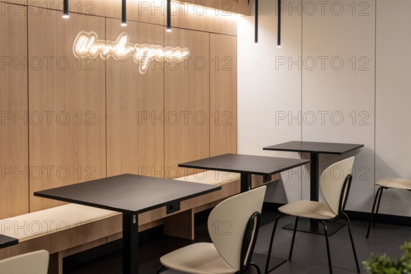 Empty tables and chairs illuminated by modern light fixtures create a workspace in an airport