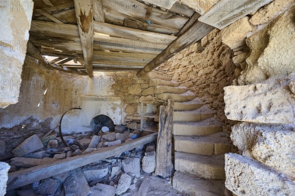 The interior of an old, abandoned mill with stone staircase and decaying wooden beams, windmill,