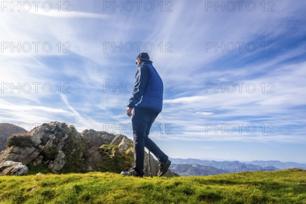 Male hiker using a walking stick while enjoying a sunny day on the summit of mount penas de aya or